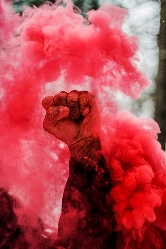 A raised fist inside a red smoke cloud