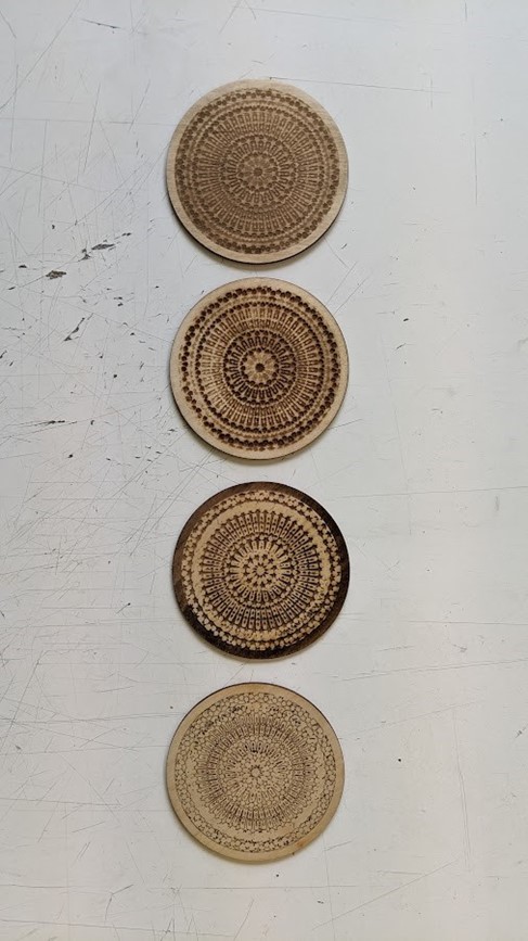 4 round pieces of veneer are laid out in a vertical line on a white surface. They are engraved with Moroccan geometrical patterns. Image source: Claude-Olivier Guay