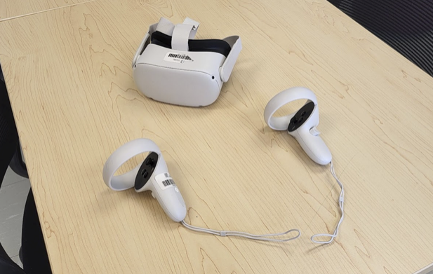 Un casque de réalité virtuelle et ses 2 manettes sont placés sur l'une des tables de travail du LEP.